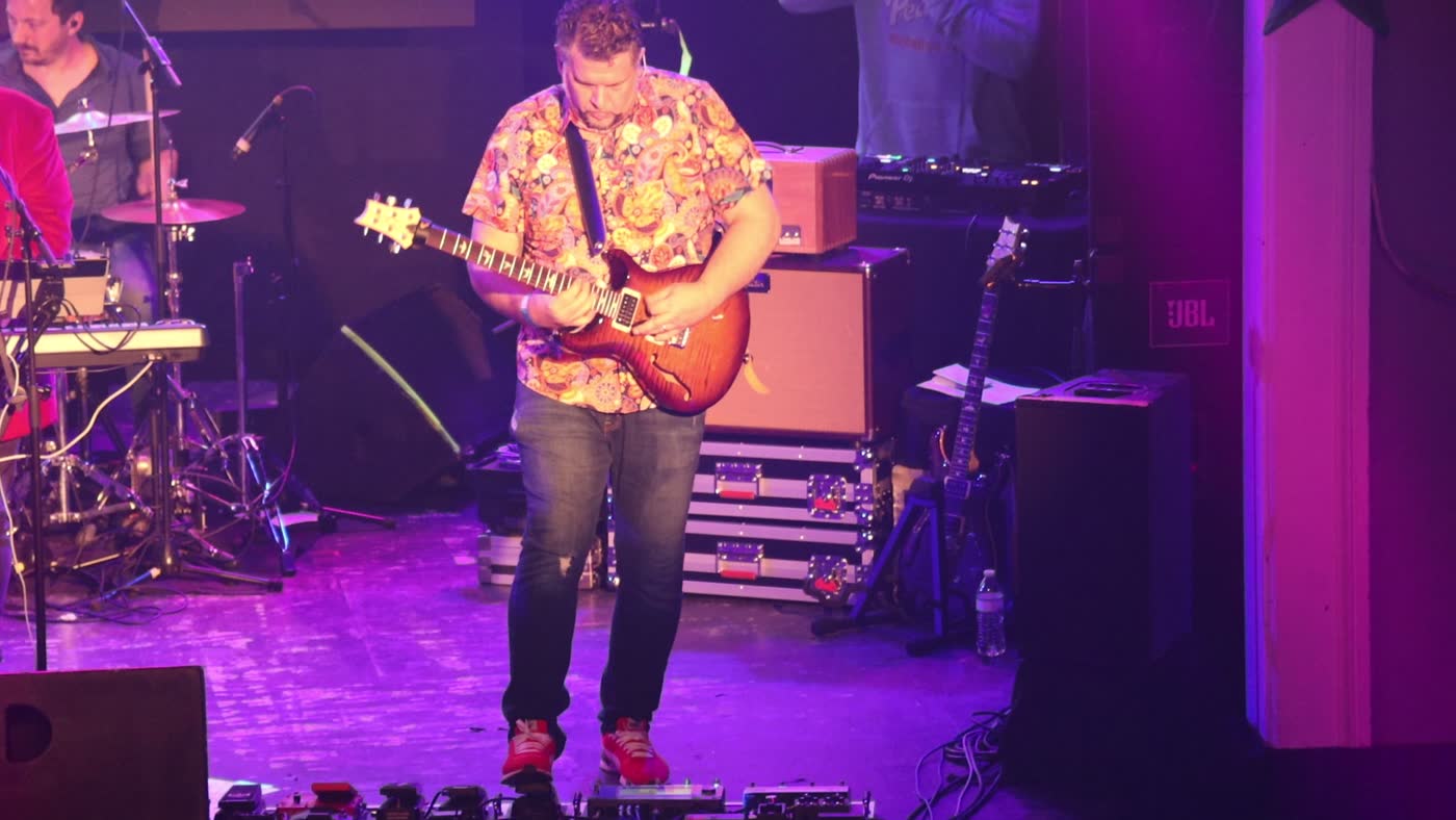 Guitarist mid-song under stage lighting